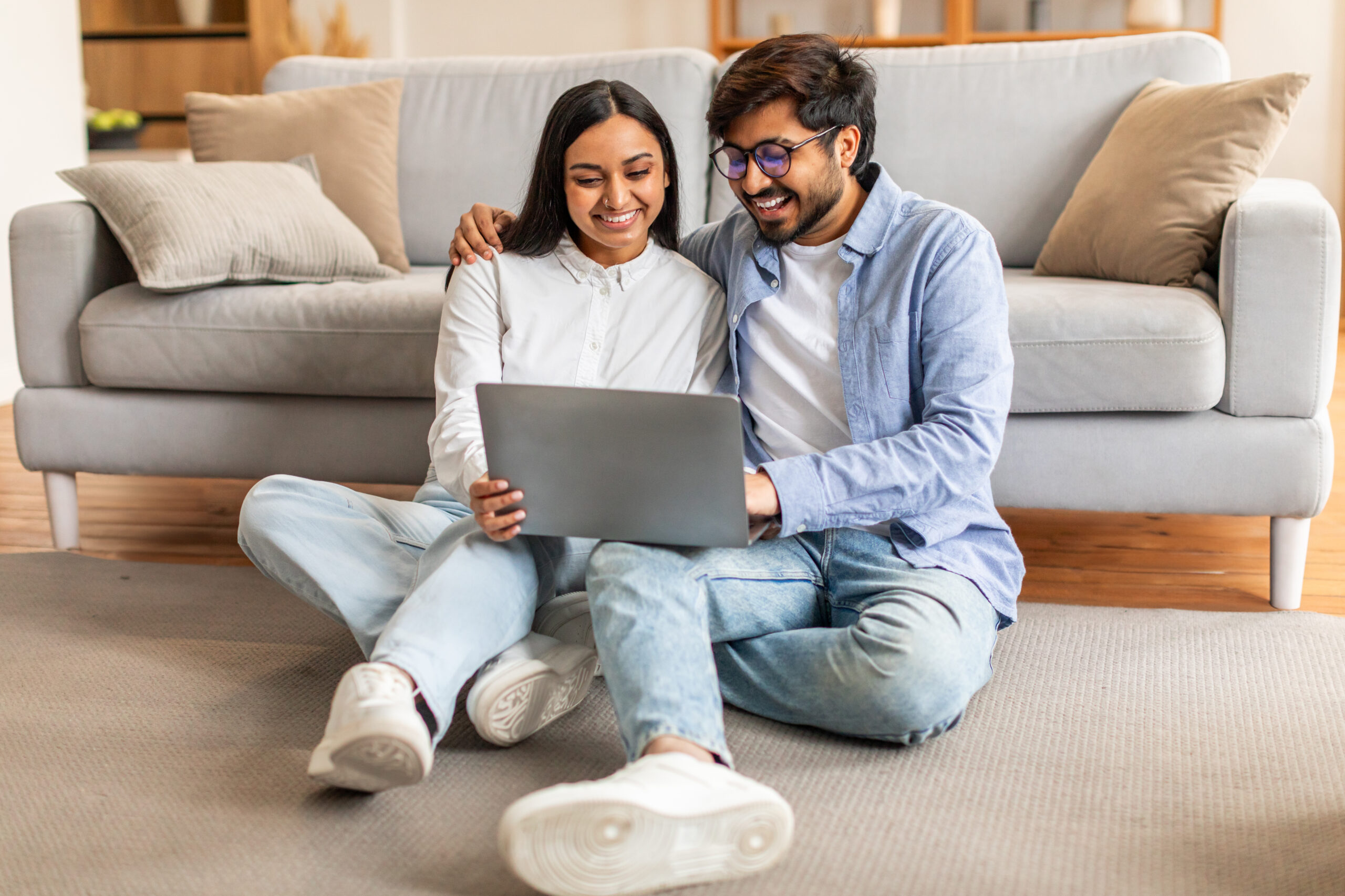 Man and Woman Sitting on Floor Looking at Laptop